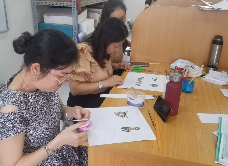 Giáo viên dùng thước, bút chì để định vị vị trí sẽ dán hình nổi vào trang phôi sách.