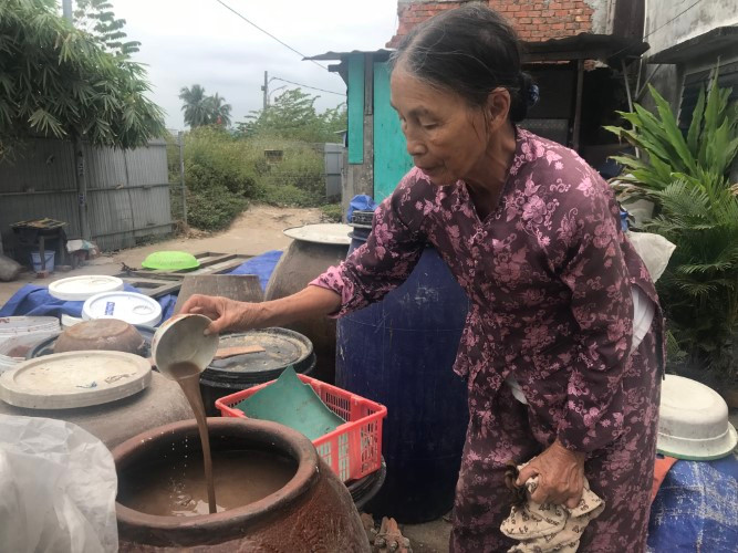 Bà Lự bên lu nước mắm đang làm. 