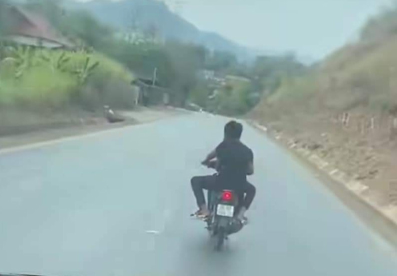 Hai thanh niên không đội mũ bảo hiểm điều khiển xe máy đánh võng trên Quốc lộ ngày 21/2.