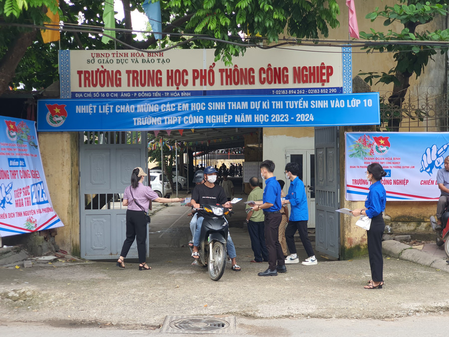 Thanh niên tình nguyện và phụ huynh đứng ở cổng trường hỗ trợ thí sinh. Thanh niên tình nguyện và phụ huynh đứng ở cổng trường hỗ trợ thí sinh.