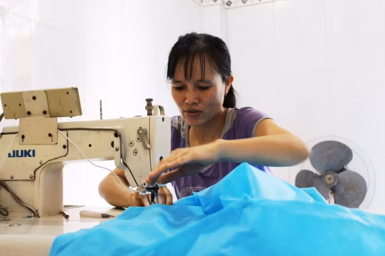 Chị Lê Thị Huệ tranh thủ nhận may đồ bảo hộ phòng dịch Covid-19 tại nhà.