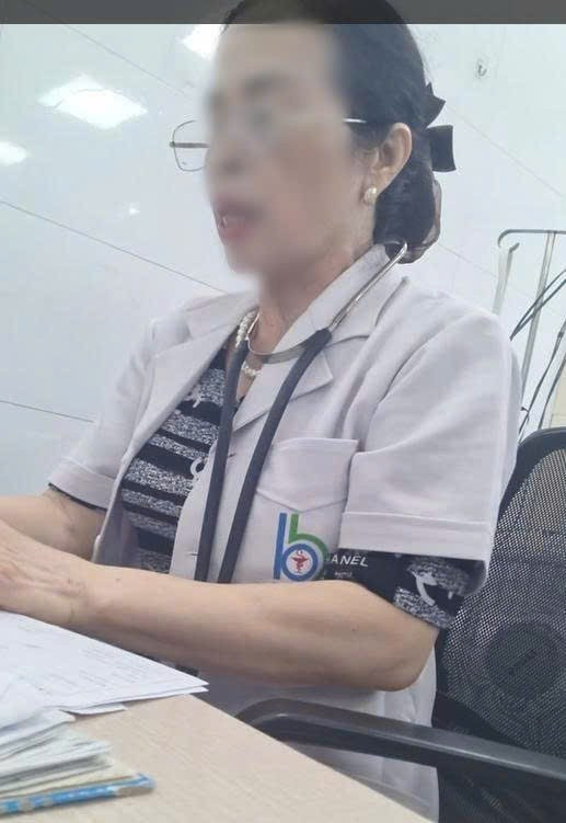 Người phụ nữ đứng tuổi khám bệnh tại phòng 102 không đeo biển tên. Tay cầm con dấu khắc sẵn chức danh đóng vào các tờ giấy khám bệnh - (Ảnh: cắt từ video). z6694102915163-25b532662caab4f795e708e32366e52a.jpg