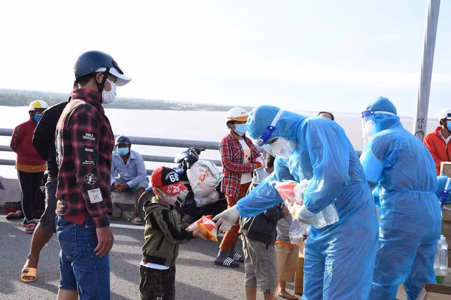 Lực lượng chức năng phát thực phẩm, nước uống cho người dân về quê.