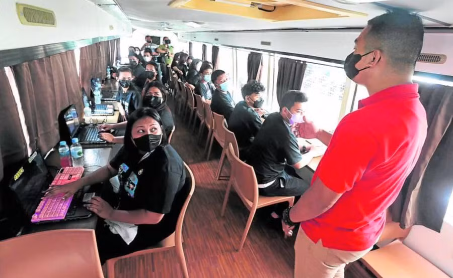 Học viên từ cộng đồng Smokey Mountain ở quận Tondo của Manila tham gia buổi học “thí điểm” trên chiếc xe buýt được chuyển đổi thành lớp học lưu động.