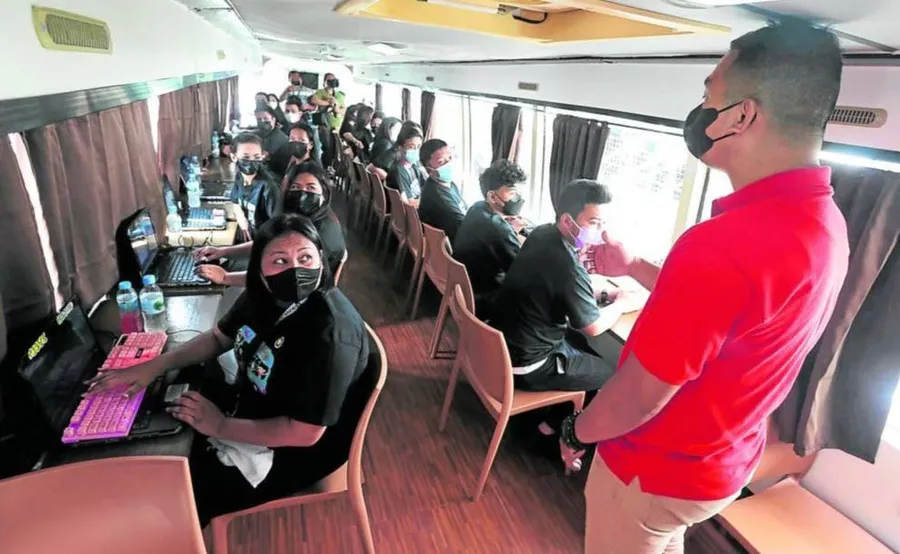 Học viên từ cộng đồng Smokey Mountain ở quận Tondo của Manila tham gia buổi học “thí điểm” trên chiếc xe buýt được chuyển đổi thành lớp học lưu động.