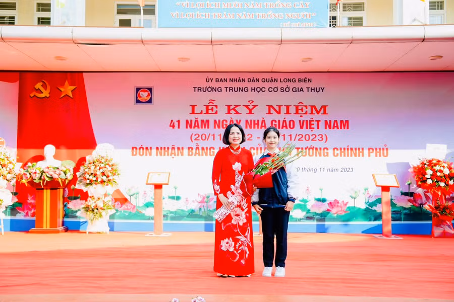 Em Nguyễn Thiên Mỹ, học sinh lớp 9A6 đại diện hơn 1.800 học sinh Trường THCS Gia Thụy tặng hoa chúc mừng cô Hiệu trưởng Nguyễn Thị Mỹ Linh.