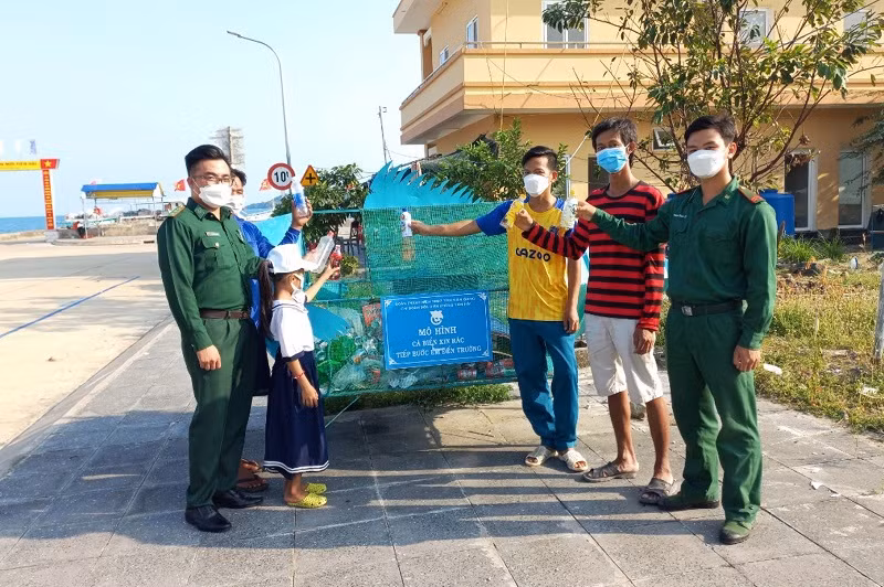 Chiến sĩ đồn Biên phòng Tiên Hải hướng dẫn du khách và các em học sinh bỏ rác thải sau khi sử dụng đúng nơi quy định.