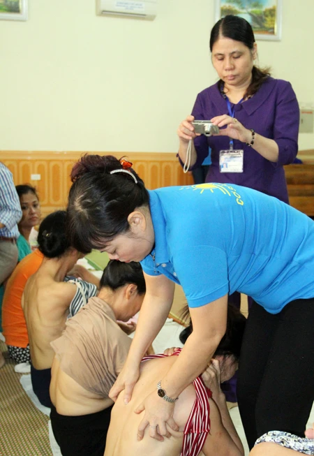 Thành viên đoàn kiểm tra liên ngành (áo sẫm, đứng sau) ghi hình quá trình hành nghề của bà Phạm Thị Phú - Chủ cơ sở tẩm quất Ban Mai (áo xanh)