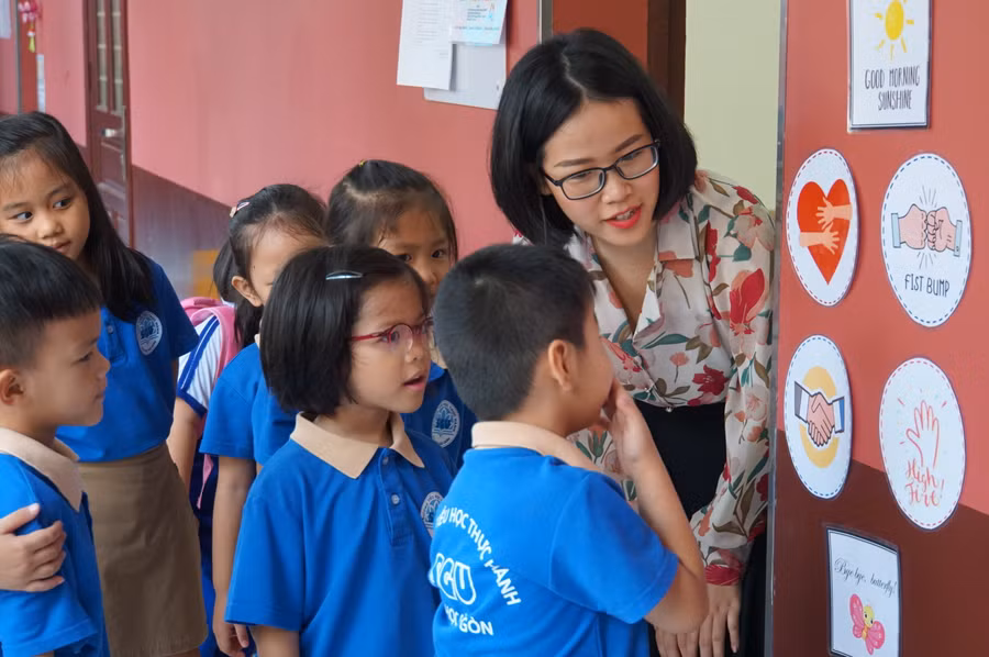 Học sinh Trường Tiểu học Thực hành ĐH Sài Gòn chọn các biểu tượng ôm, cụng tay... với cô giáo trước khi vào lớp.