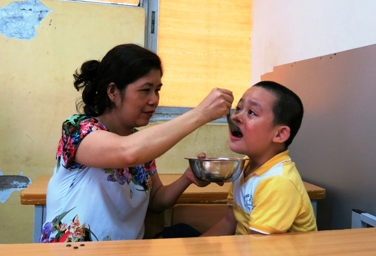 Cô Thủy dỗ dành trò khuyết tật trong giờ ăn trưa