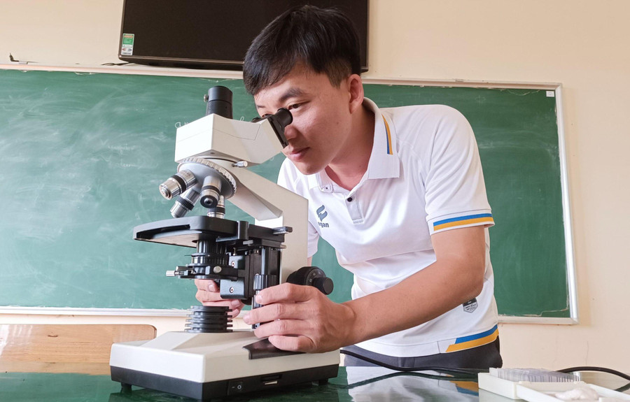 Anh Đỗ Minh Hưng - nhân viên thiết bị Trường THPT Trần Hưng Đạo kiểm tra kính hiển vi trước khi bàn giao cho giáo viên. Ảnh: Thành Tâm