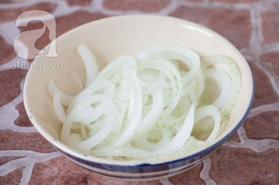 Hành tây bóc vỏ, thái khoanh mỏng, trộn cùng vài giọt chanh để hành tây dịu lại, bớt hăng.