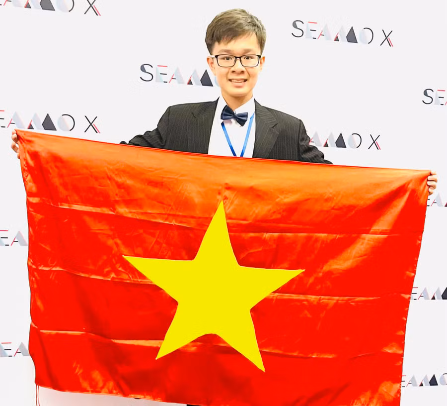 Huy Hoàng tự hào cầm lá cờ đỏ sao vàng Việt Nam tại giải Toán quốc tế.
