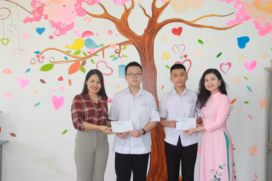 Ban giám hiệu và cô giáo chủ nhiệm trao phần thưởng chúc mừng thành tích của 2 tân thủ khoa.