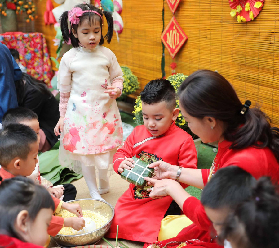 Cô giáo Trường Mẫu giáo Mầm non A hướng dẫn học sinh gói bánh chưng. Ảnh: TG Cô giáo Trường Mẫu giáo Mầm non A hướng dẫn học sinh gói bánh chưng. Ảnh: TG