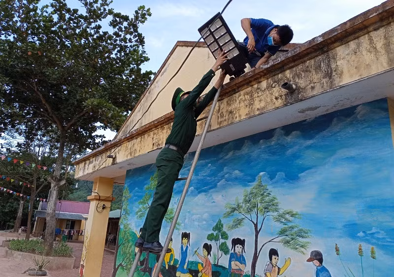 Giáo viên Trường Tiểu học Mỹ Lý 2 và bộ đội Biên phòng lắp đèn năng lượng mặt trời ở khuôn viên sân trường. 