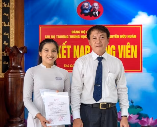 Thầy Đỗ Dương Cung - Phó Bí thư Chi bộ, Phó Hiệu trưởng Trường THPT Nguyễn Hữu Huân trao quyết định cho em Bùi Thị Minh Châu trong Lễ kết nạp Đảng vào tháng 7/2020. Ảnh: NTCC