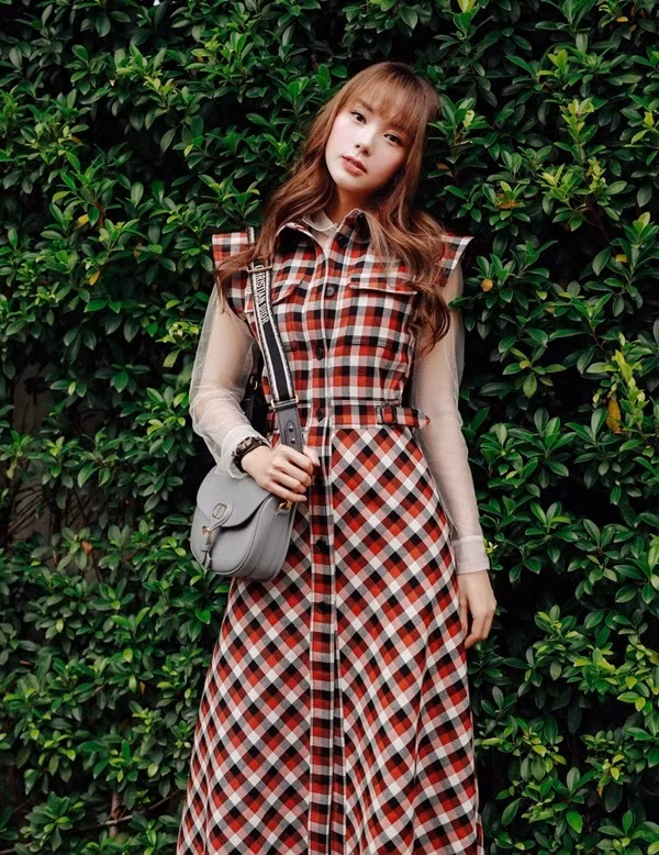 Minh Hằng trẻ trung khi phối layer chiếc đầm kẻ tartan với áo xuyên thấu. Cô nàng còn khéo léo tạo điểm nhấn cho bộ cánh street style bằng chiếc túi Bobby, phiên bản màu xám của Dior.