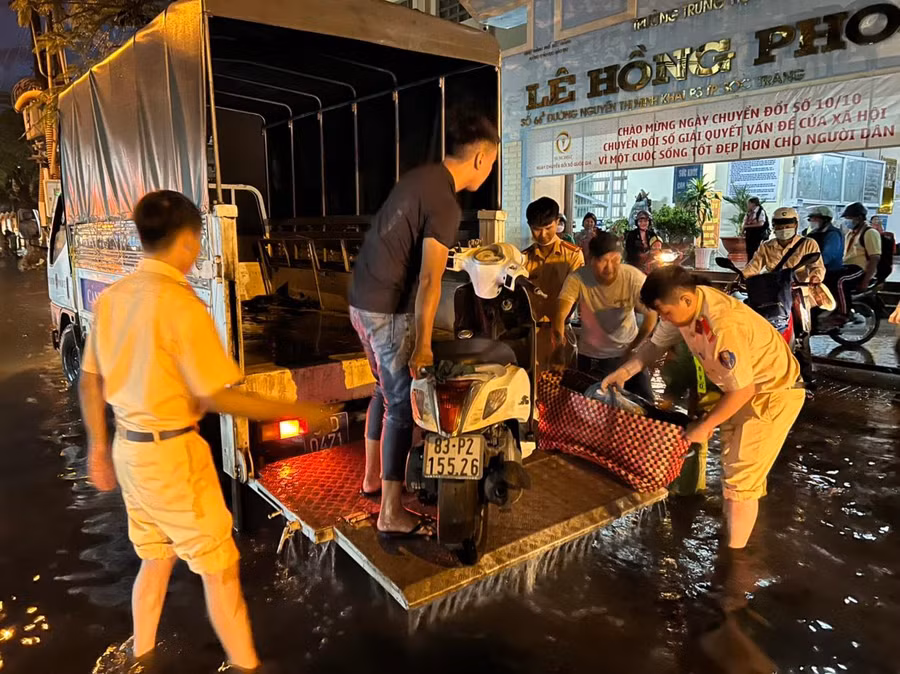 Lực lượng chức năng hỗ trợ người dân, xe máy qua khỏi khu vực ngập nước.