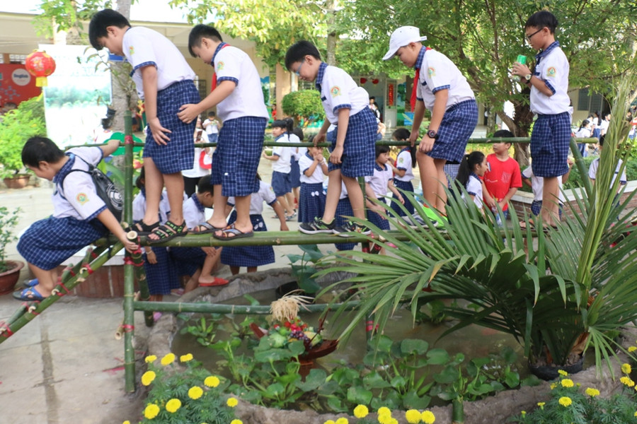 Các em học sinh thích thú trải nghiệm đi cầu khỉ chỉ có ở vùng quê.