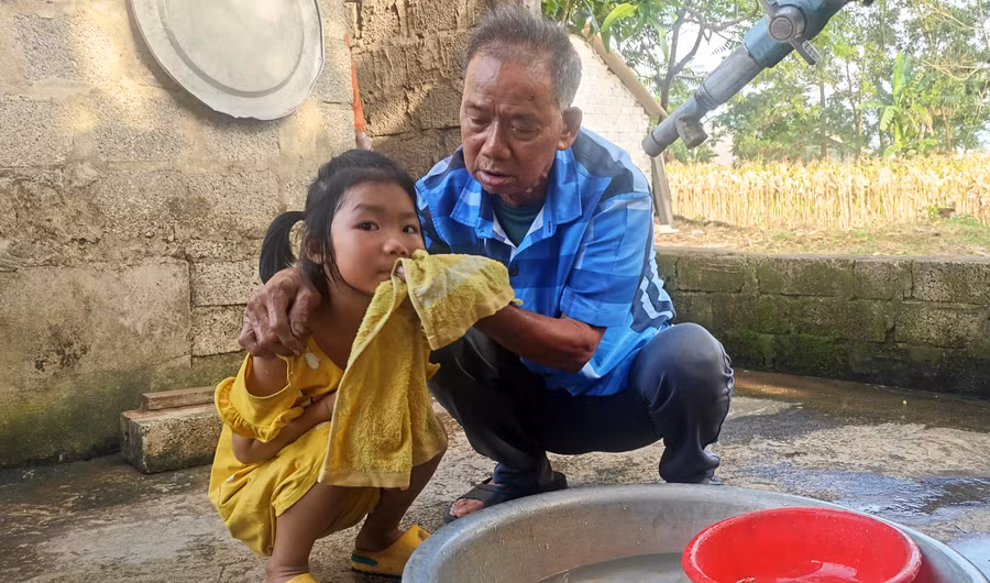 Cụ ông Hoàng Đình Nhiền chăm sóc đứa cháu nội mồ côi cha.