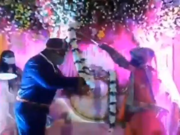 Cặp đôi người Ấn Độ dùng que tre để trao vòng hoa tín vật nhằm giữ khoảng cách trong đám cưới.