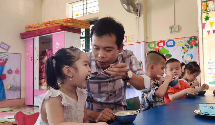 Thầy giáo Trịnh Hồng Quân – Hiệu trưởng Trường Mầm non Thành Sơn (Bá Thước, Thanh Hóa) đang cho trẻ ăn trưa tại trường.