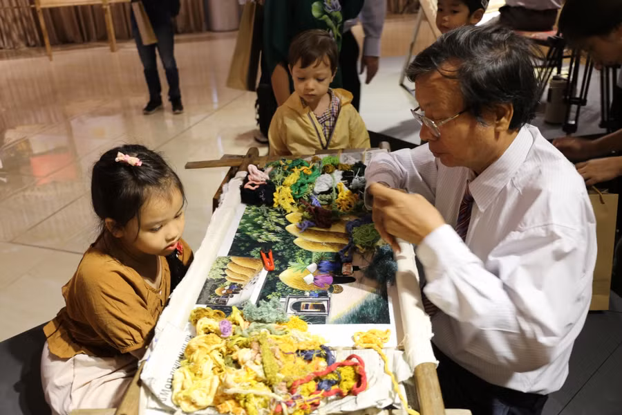 Nghệ nhân Nguyễn Xuân Dục (thôn Bình Lăng, xã Thắng Lợi, huyện Thường Tín) đang hướng dẫn cho những vị khách “nhí” tới triển lãm cách thêu tranh.