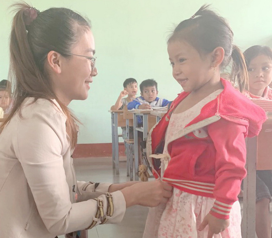 Cô Đặng Thị Ngọc mặc áo ấm cho HS Đinh Thị Thiếp. Ảnh: TG