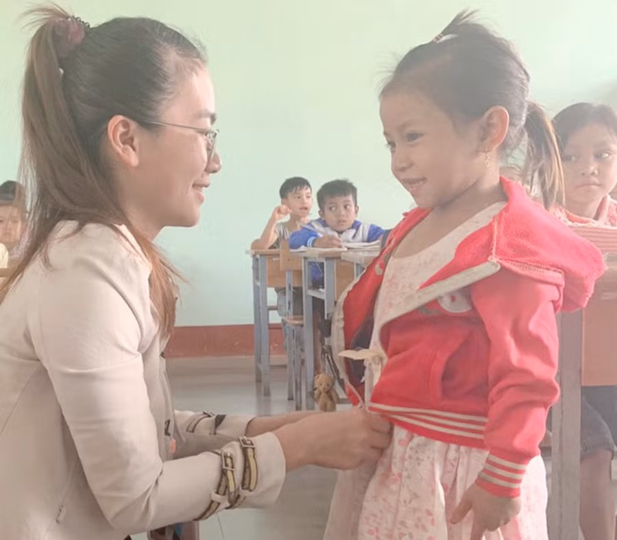 Cô Đặng Thị Ngọc mặc áo ấm cho HS Đinh Thị Thiếp. Ảnh: TG