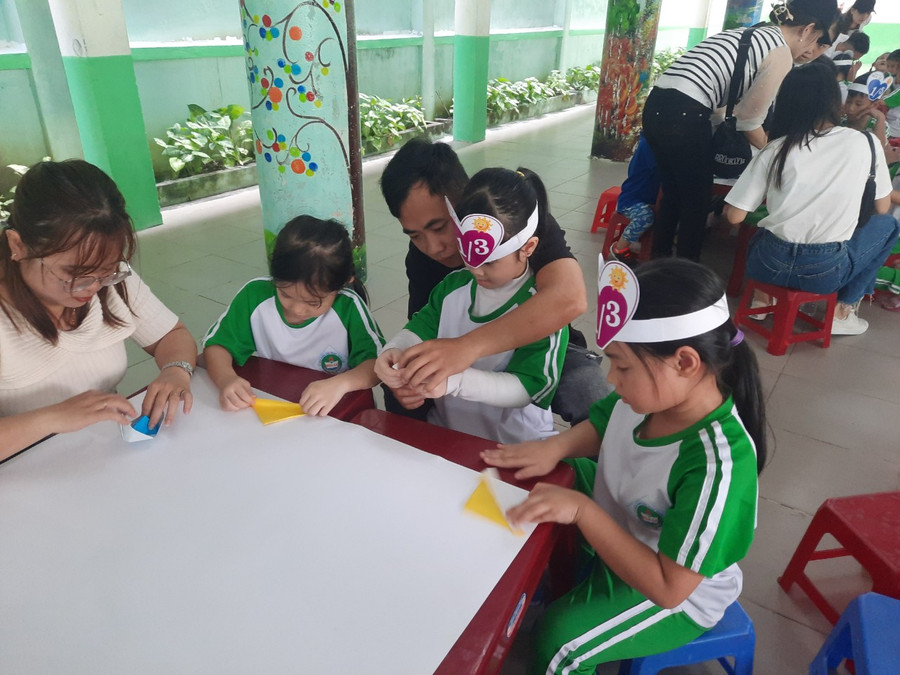 Một phụ huynh hướng dẫn con gái gấp thuyền giấy ở nội dung thi cùng vẽ, xé giấy. (Ảnh: PV). Một phụ huynh hướng dẫn con gái gấp thuyền giấy ở nội dung thi cùng vẽ, xé giấy. (Ảnh: PV).