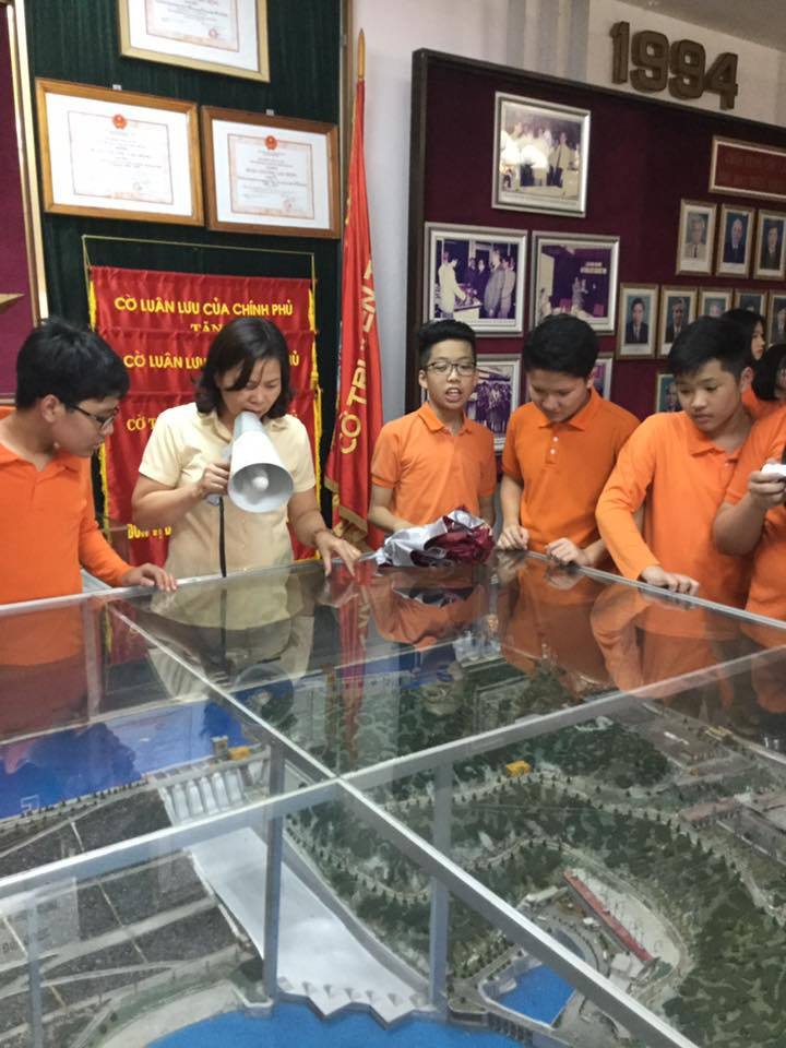 Học sinh lắng nghe cô nhân viên thuyết minh về sa hình nhà máy