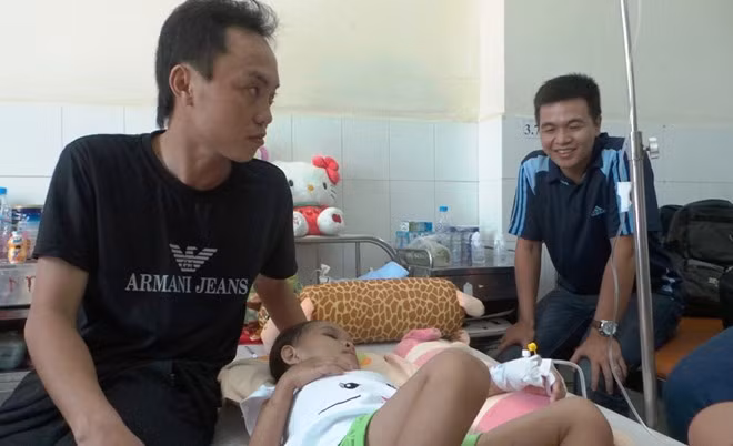 Anh Trần Văn Tố - cha ruột bé Ngân chăm sóc con bên giường bệnh.