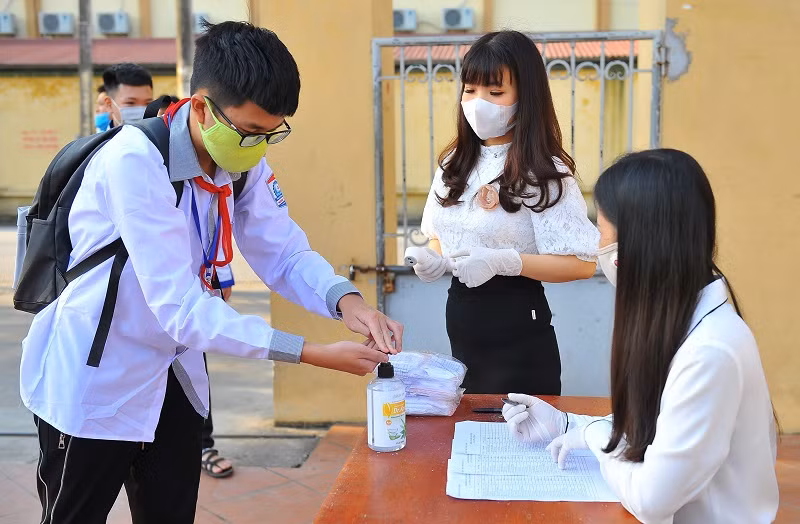 Nhân viên y tế học đường hướng dẫn học sinh Trường THCS Ninh Thành (Ninh Bình) sát khuẩn tay trước khi vào trường.