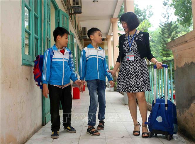 Cô giáo Trần Thị Thu Hiền giúp đỡ học sinh Nguyễn Khắc Hoàng Anh (bị khuyết tật cả vận động và trí tuệ) sau giờ tan học. Ảnh: Thanh Tùng/TTXVN