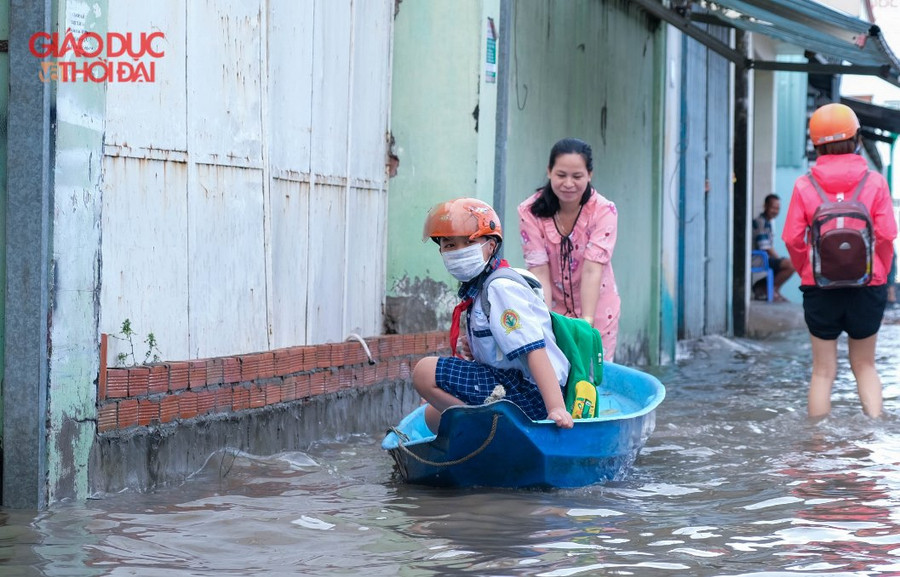 Một phụ huynh đưa con đến trường bằng xuồng.