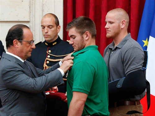 Tổng thống Pháp Francois Hollande (trái) trao huân chương cho vệ binh quốc gia Mỹ Alek Skarlatos trong khi binh sĩ không quân Spencer Stone (phải) nhìn theo trong buổi lễ. Ảnh: Reuters French President Francois Hollande (left) awards National Guardsman Alek Skarlatos (center) with the Legion d