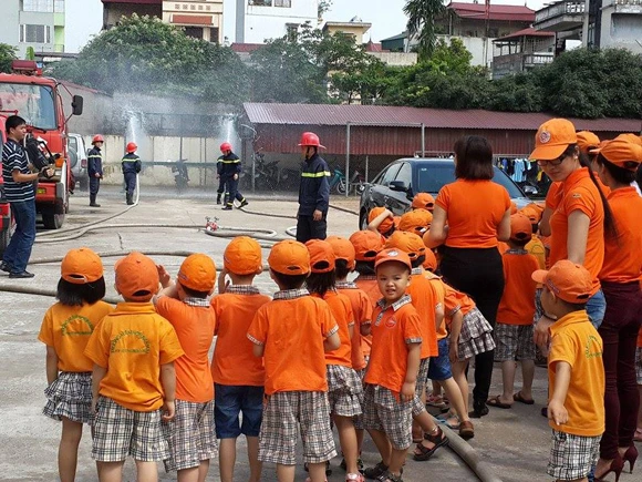 Giáo viên và học sinh mầm non xem công tác tập luyện và triển khai đội hình chữa cháy của các chiến sĩ chữa cháy