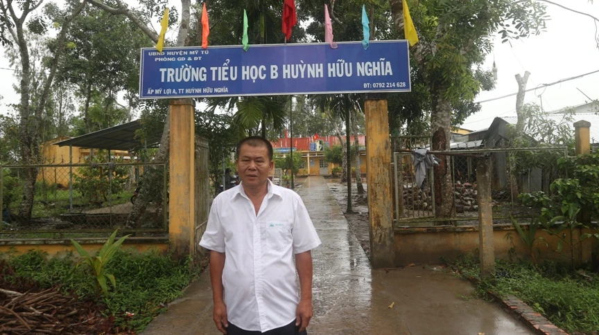 Ông Trần Văn Đôi bên Trường Tiểu học B Huỳnh Hữu Nghĩa - nơi ông hiến đất xây dựng