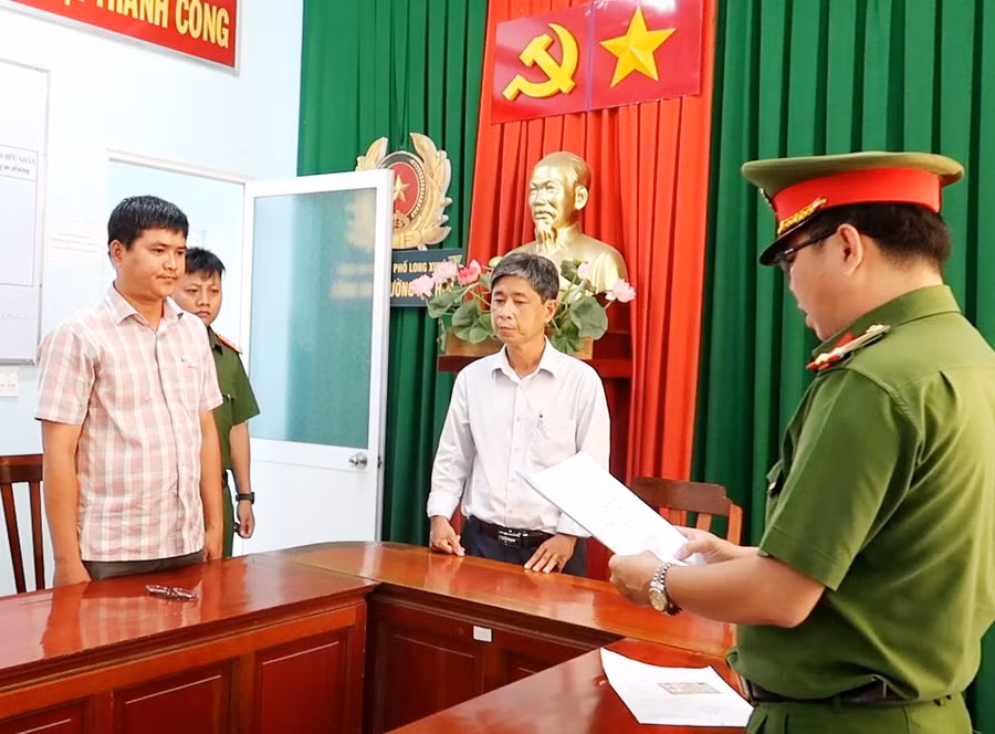 Cơ quan Công an tống đạt các Quyết định và Lệnh bắt tạm giam đối với bị can Nguyễn Thanh Phong (áo sọc). (Ảnh: Tiến Tầm)