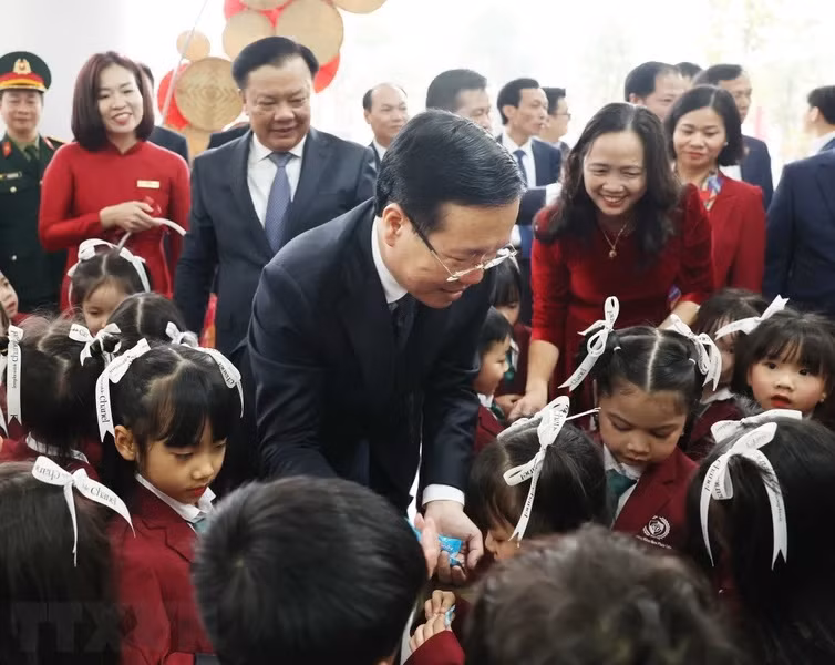 Chủ tịch nước Võ Văn Thưởng chia kẹo cho các cháu nhi đồng tại Trường Mầm non Phúc Lộc, xã Uy Nỗ, huyện Đông Anh. (Ảnh: Thống Nhất/TTXVN)