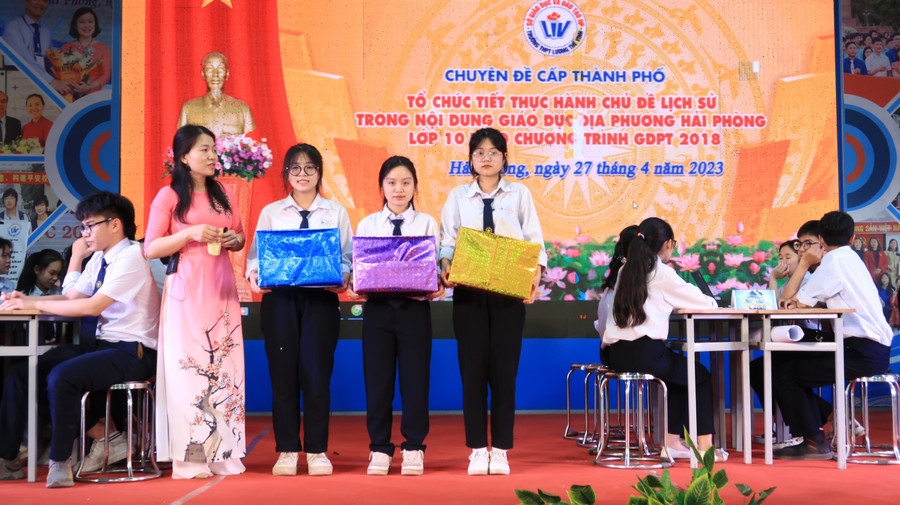 Cô giáo tổng kết, đánh giá và khen thưởng nhóm học sinh đạt điểm cao trong khi thực hiện nhiệm vụ được giao.