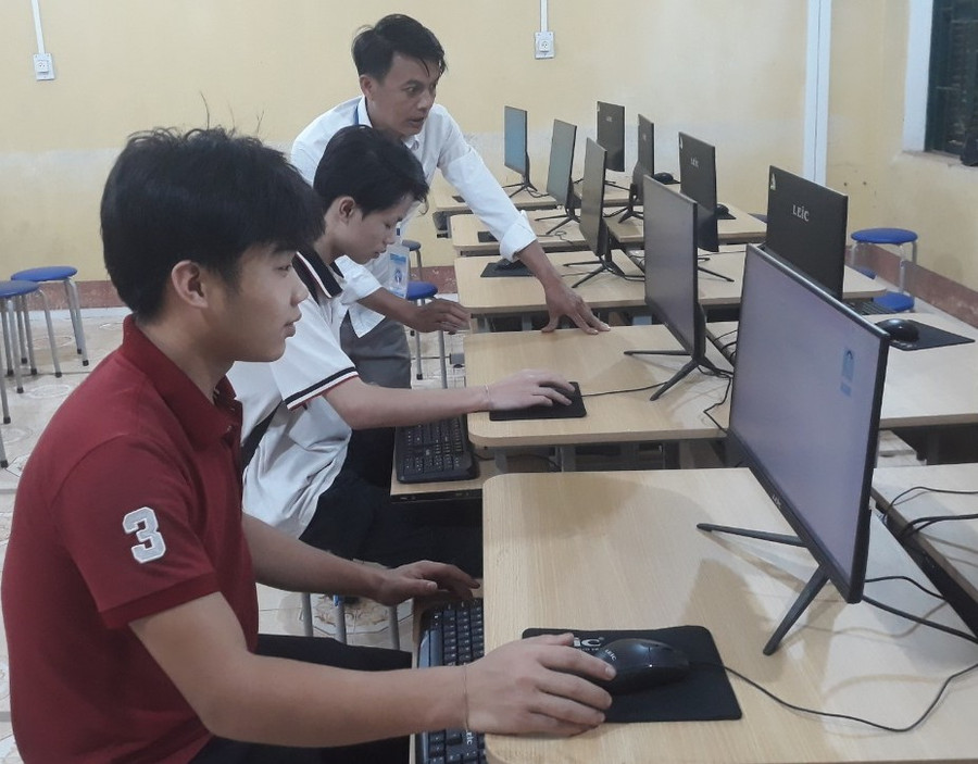 Thầy Xa Văn Mạnh - Trường THPT Mường Chiềng hướng dẫn học sinh đăng ký dự thi chiều 2/5.Ảnh: NTCC