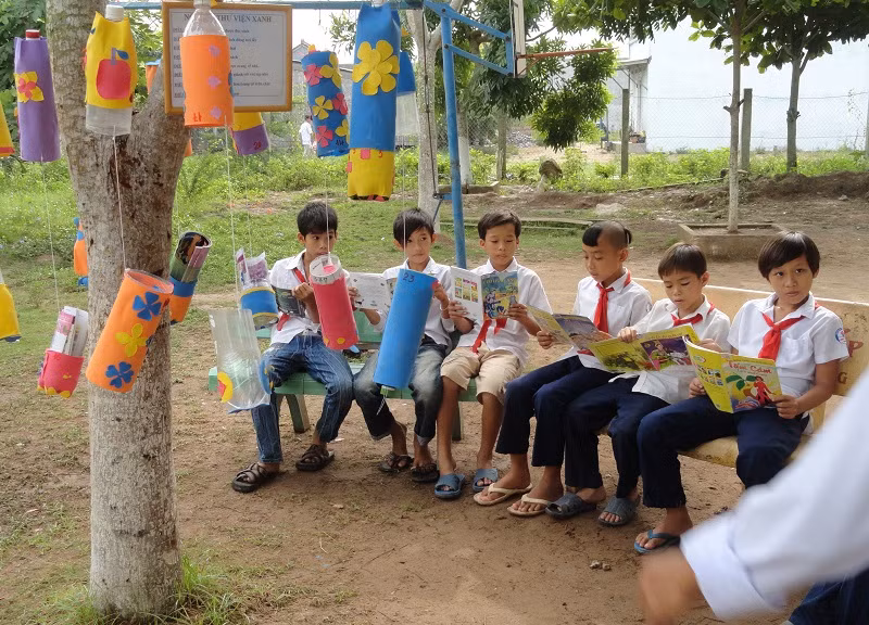 Các em HS thích thú ngồi đọc sách tại Thư viện xanh dưới gốc cây, ghế đá.