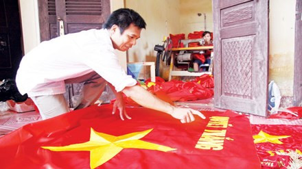 Anh Phục đang kiểm tra lá cờ sau khi hoàn thiện.