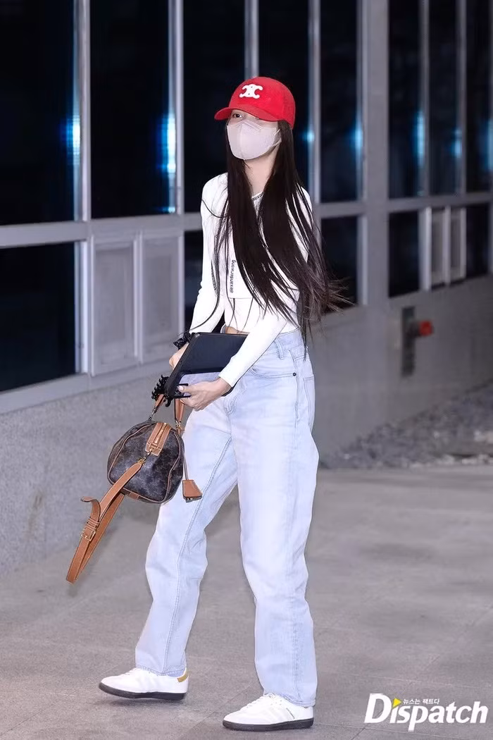 Lisa đội mũ lưỡi trai đỏ, khoác sơ mi dài tay và quần jeans đến sân bay.