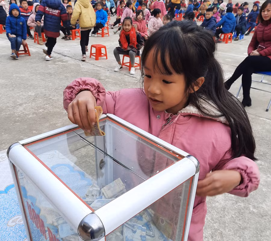Học sinh Trường Tiểu học số 1 Quài Nưa quyên góp tiền ủng hộ bạn bị lốc xoáy gây tốc mái, hư hại nhà. Ảnh: NTCC