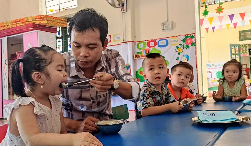 Thầy giáo Trường Mầm non Thành Sơn (Bá Thước, Thanh Hóa) cho trẻ ăn trưa tại trường.
