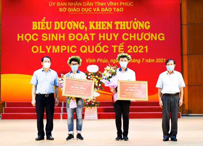 Ông Nguyễn Phú Sơn - Giám đốc Sở Nội vụ và ông Trần Dũng Long - Phó Chủ tịch thường trực Hội Khuyến học tỉnh Vĩnh Phúc (ngoài cùng bìa phải) trao quà của Quỹ - Hội Khuyến học tỉnh cho hai học sinh đoạt huy chương Olympic quốc tế 2021.