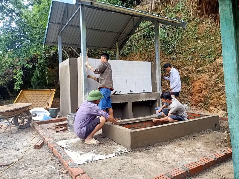 Giáo viên hỗ trợ xây dựng nhà vệ sinh tại Trường Mầm non Sa Dung.